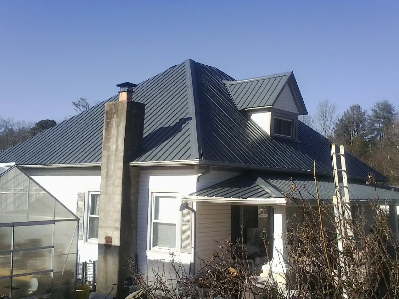 Dark blue standing seam metal roof on a white farmhouse with dormer — Slate & Tile Roof Repair by Roofing Brothers in North Chicago