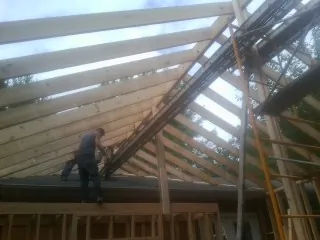 Rafters going up over a new addition with a worker on the wall in North Chicago