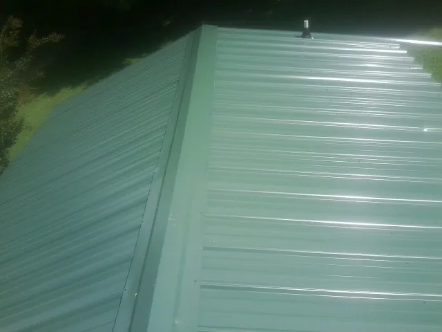 New green metal panels meeting at the ridge of a roof — Flat Roof Repair work by our crew in North Chicago