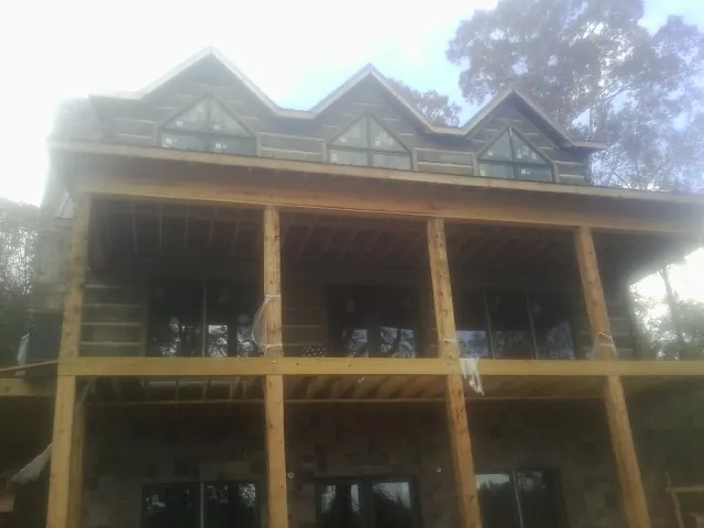 Dormers and porch framing on a large log home under construction — Roof Coating work by our crew in North Chicago