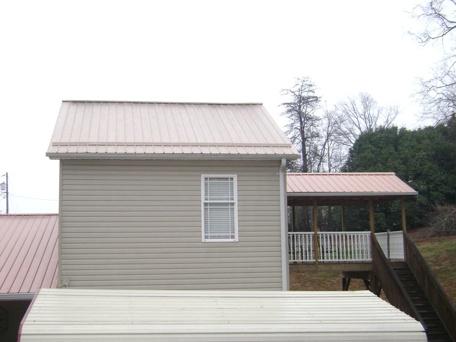Tan metal roofs on a two story addition and attached porch, from a Roof Replacement job in North Chicago