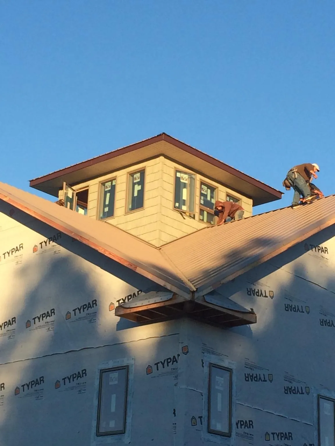 Roofers working around a rooftop cupola on a new metal roof at sunset — Roof Waterproofing in North Chicago by Roofing Brothers